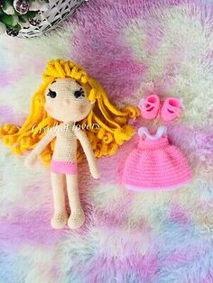 a crocheted doll next to a pink and yellow dress on a fuzzy surface