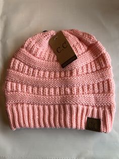 a pink knitted beanie hat with a tag on the front and back of it