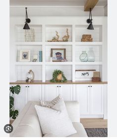 a living room filled with lots of white shelves and decor on top of it's walls