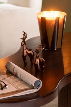 a table with a candle, glasses and magazine on it next to a glass vase