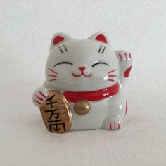 a white cat figurine with chinese writing on it's chest and eyes closed