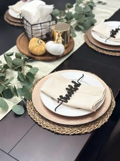 the table is set with white and black plates, napkins, and pumpkins