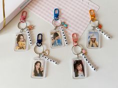 four personalized key chains with pictures attached to them, sitting next to a pink and white checkered envelope