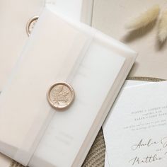 a wedding ring sits on top of an open book next to a feather quill