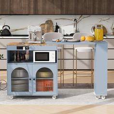 a kitchen area with a microwave, oven and counter top in blue painted cabinetry