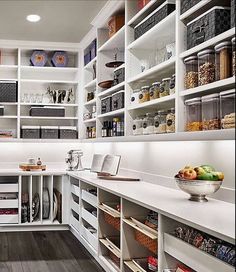 a kitchen with white cabinets and shelves filled with food