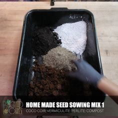 a person scooping some dirt into a black pan on top of a wooden table