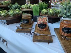 a table topped with jars filled with food next to wooden cutting boards and utensils