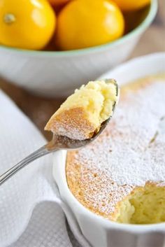 a spoon with some food in it on top of a table next to a bowl of oranges