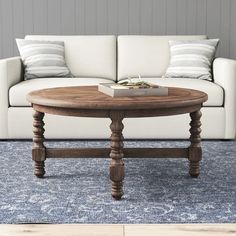 a living room with a white couch and wooden table in the middle, on a blue rug