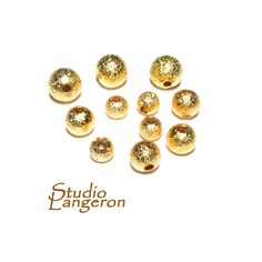 gold glittered round beads on white background with studio langgeron logo in the middle