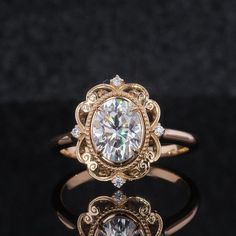 a fancy ring with an oval cut diamond surrounded by smaller round diamonds on a black surface