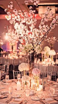 an elegant centerpiece with flowers and candles is displayed on a round table in the middle of a banquet hall