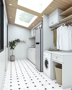 a laundry room with white cabinets and black and white tile flooring that has a skylight above the washer and dryer