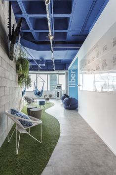 an office with artificial grass on the floor and blue painted ceiling, along with hanging hammocks