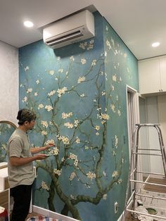 a man is painting a mural on the wall in a room with blue and white walls