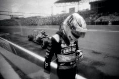 a black and white photo of a person in a racing suit on a race track