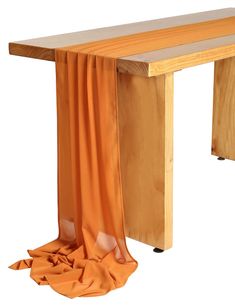 a wooden bench with an orange cloth draped over it's legs and bottom section