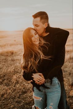 a man and woman hugging in an open field