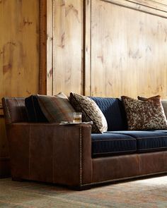 a couch with pillows on it sitting in front of a wooden paneled room wall