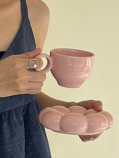 a woman holding a pink coffee cup and saucer