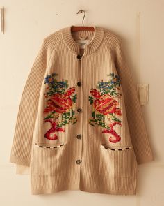 This jacket is inspired by a crochet blanket, circa 1850s-1870s. It features a faithful reproduction of the original motif reinterpreted as a knit with hand-embroidered details.  Elongated fit Four button closure  Two front pockets 100% wool   Made in Peru Dry clean only View all knitwear All wear, mending, and idiosyn Beige Cardigan With Floral Embroidery For Fall, Beige Floral Embroidered Cardigan For Fall, Traditional Outerwear With Button Closure For Fall, Embroidered Knit Long Sleeve Outerwear, Beige Wool Knitted Sweater Coat, Beige Knitted Wool Sweater Coat, Fall Embroidered Beige Cardigan, Bohemian Winter Outerwear With Button Closure, Embroidered Knit Outerwear For Winter