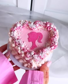 a pink heart shaped cake being held by someone