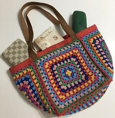 a crocheted bag with a wallet and some other items in it sitting on a table