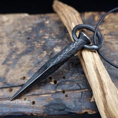 an old knife is sitting on top of a piece of wood and tied to a chain