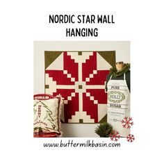 a red and white christmas quilt next to a bottle of wine with the words nordic star wall hanging on it