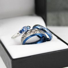 two wedding rings sitting in a box with snow on the ground around them and one is blue