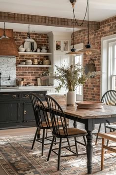 a dining room table with chairs and a potted plant on it in front of a brick wall