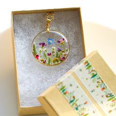 a glass pendant with flowers in it sitting on a table next to an open box