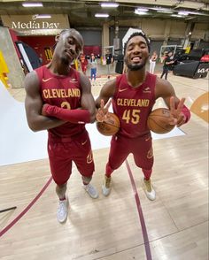 two men in red uniforms holding basketballs and posing for a photo on the court