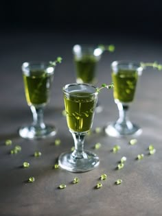 three glasses filled with green liquid and sprinkles on top of a table