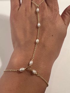 This genuine Pearl hand chain is Stunning and made by hand using genuine Swarovski rhinestones and crystals, 14k gold fill chain and clasp. Made for the Ti Adora by Alvina Valenta 2016 NY Bridal Market and LookBook photoshoot. Typical made for a 7" long hand (wrist to top of center finger):6.5" in wrist circumference with .5" additional adjustable clasp.3" from wrist up to the ring2.5" in ring loop circumference (non adjustable)Custom length is welcome! Just write in the measurements in the note Bracelet Connected To Ring, Ring To Bracelet Jewellery, Diy Hand Chain, Gold Pearl Chain Jewelry For Party, Party Gold Jewelry With Pearl Chain, Pearl White Metal Jewelry With Adjustable Chain, Pearl Charm Bracelet For Party, Pearl Bracelet With Pearl Drop, Gold Plated Silver Jewelry With Pearl Charm