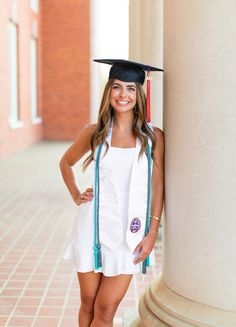 a woman in a graduation cap and gown standing next to a column with her hands on her hips