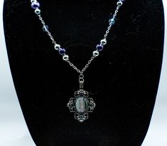 This elegant necklace is sure to turn heads. An ornate 2-in metal pendant hanging center. A pearl gradient of purple beads brings out the varying shades of the pendent as your eyes follow along the metal chain that it hangs from.  Approx. Length of 22in Lobster Clasp Purple Metal Chain Necklace Gift, Purple Metal Chain Necklace As Gift, Silver Pendant Beaded Necklace With Pearl Chain, Elegant Purple Metal Necklace, Purple Necklace With Pearl Pendant, Purple Metal Pendant Necklaces, Purple Pearl Pendant Necklace, Hanging Necklaces, Purple Beads