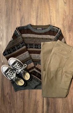 a pair of shoes, sweater and pants sitting on top of a wooden floor next to each other