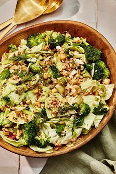 a wooden bowl filled with broccoli, nuts and other vegetables on top of a table