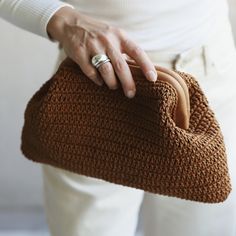 a woman is holding a brown knitted purse