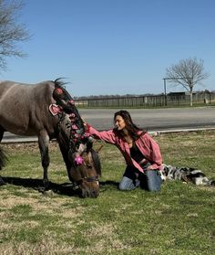 a woman kneeling down next to a horse