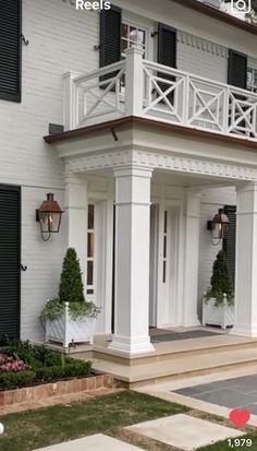 a large white house with black shutters and balconies on the second floor