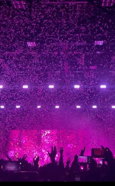 the crowd is at a concert with their hands in the air as they are surrounded by confetti