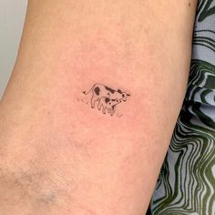 a woman's arm with a small tattoo of a cow on the left side