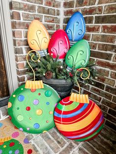 some colorful ornaments are sitting on the ground near a brick wall and potted plant