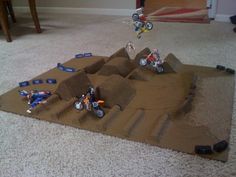 two kids are playing with legos on a cardboard race track in the living room