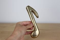 a hand holding a golden musical note on top of a wooden table