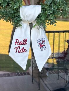 two white towels hanging from the side of a door with red and white ribbons attached to it