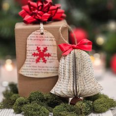 an ornament with a red bow on it next to a book and christmas tree